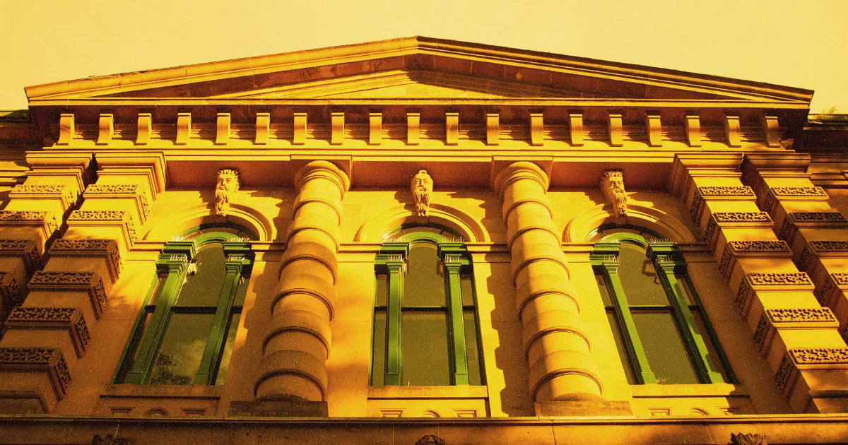The ornate carved stone facade of the Nova Scotia Law Courts building, with arched windows, columns, and statuary lit by warm evening light
