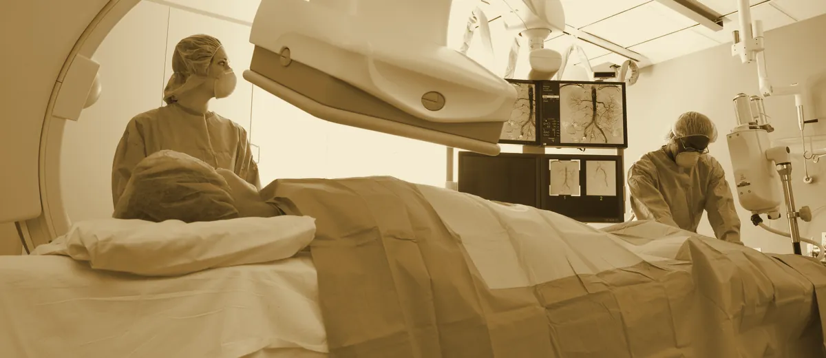 A patient undergoing medical imaging with an attending technologist to screen for cancer