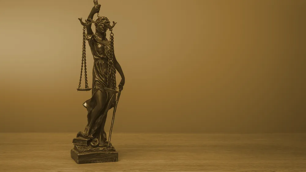 A bronze Lady Justice statue on a wooden table