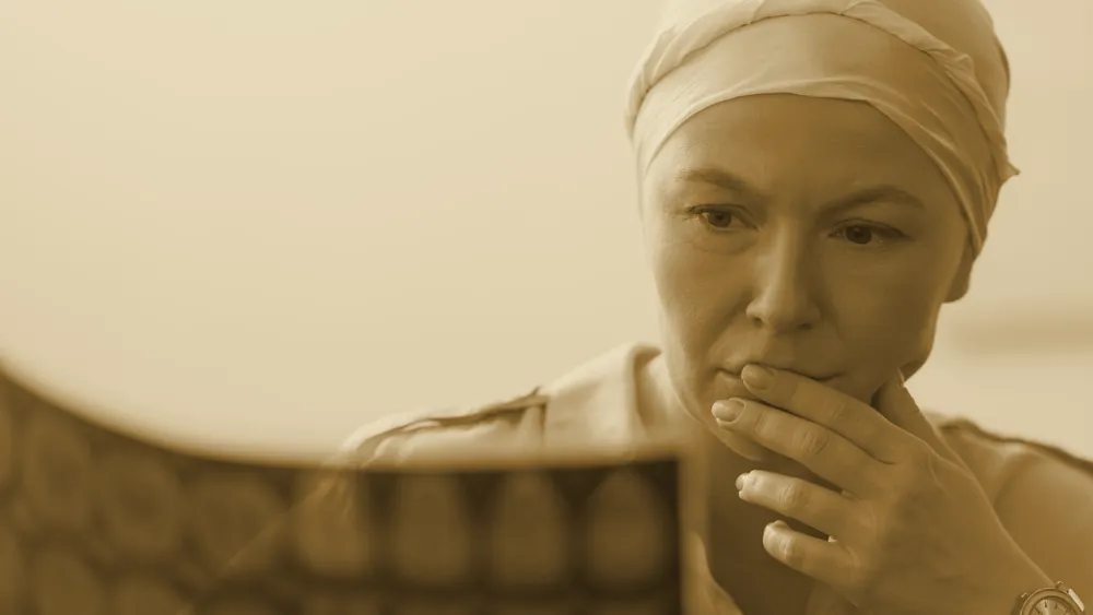 A close-up of a serious, unwell mature woman wearing a headscarf