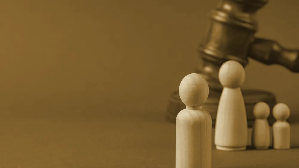 Small wooden figures beside a gavel on a grey background