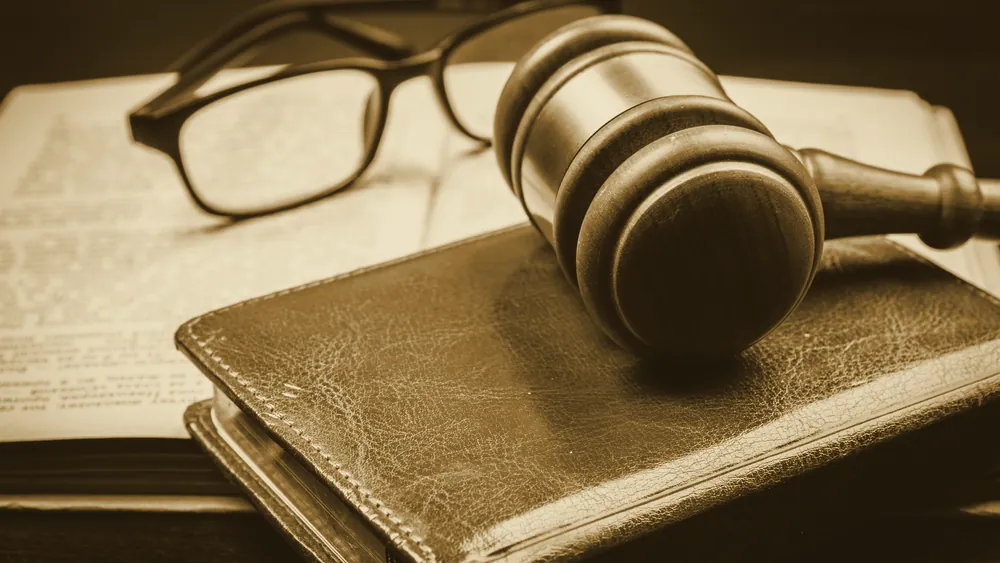 A gavel, a law book, and reading glasses on a desk