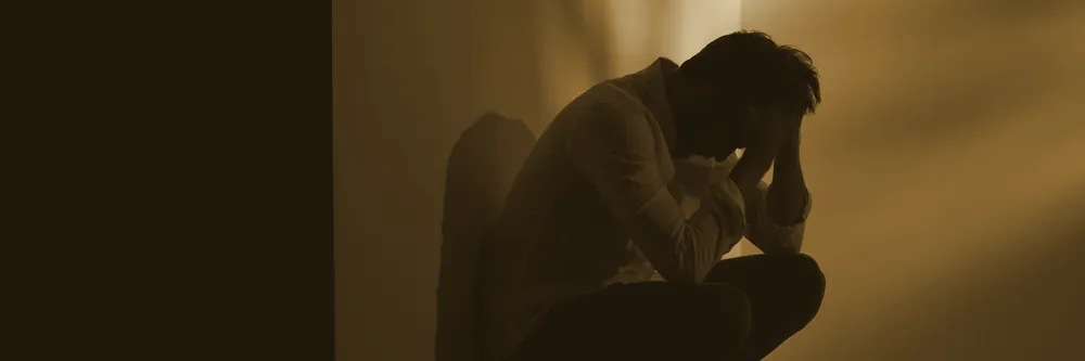 A man crouching with his head in his hands